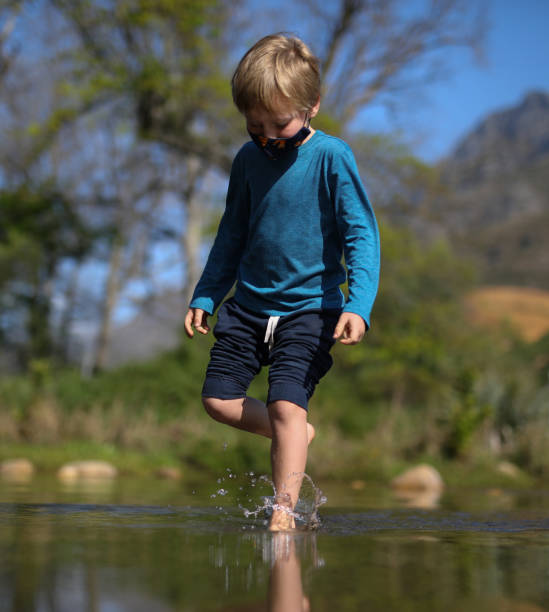 istock A blond boy walking barefoot across a low water bridge 1276736293