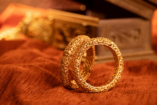 Fancy designer antique golden bracelets for woman fashion studio shot with decorate background.
