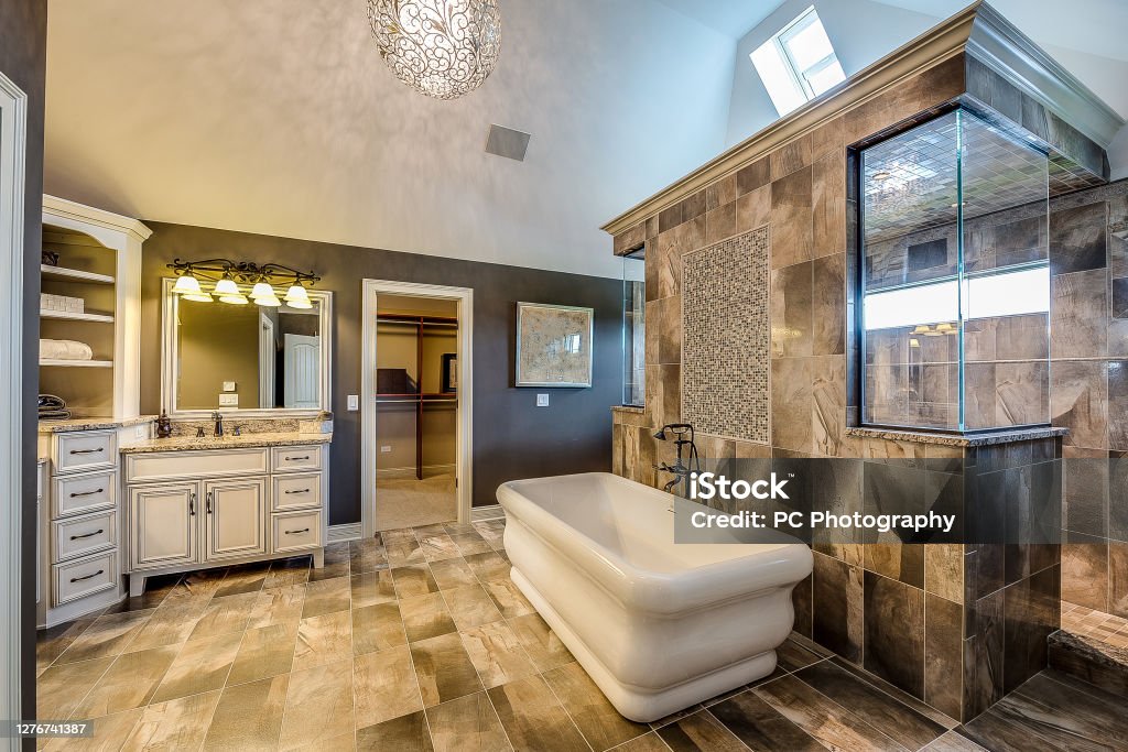 Gorgeous walk-through shower Freestanding tub outside large shower with brown tile Bathroom Stock Photo