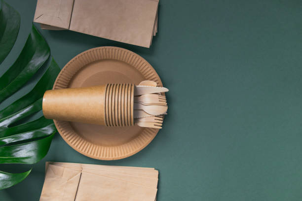 istock Eco friendly craft paper tableware on green background with monstera leaf. Recycling concept. 1276741546