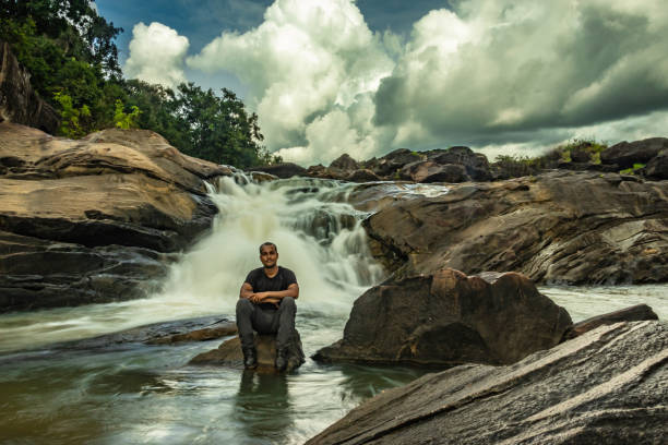 istock man sitting at a rock watching the beautiful waterfall stream at evening 1276743584