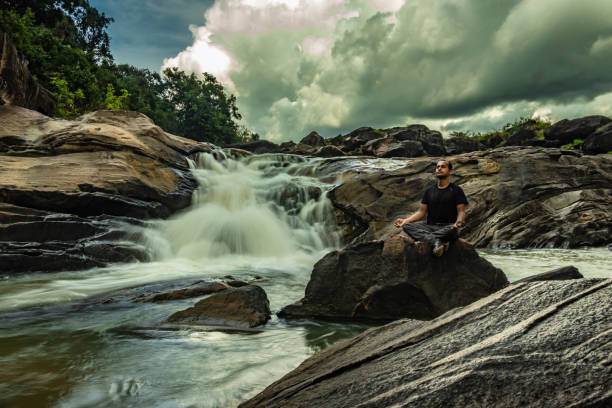 istock man meditating at the rock with the beautiful waterfall stream at the evening 1276743647