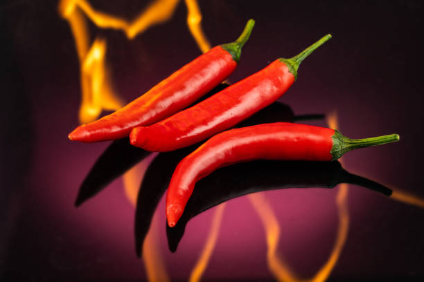 red hot long chili peppers burning on fire on a red dark background