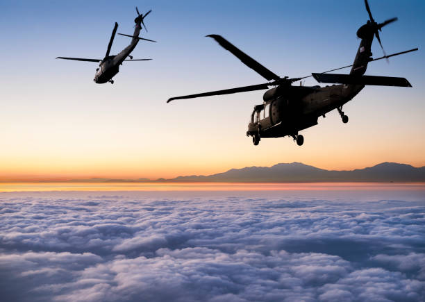 istock Two flying army helicopters over cloud sea at sunrise 1276747226