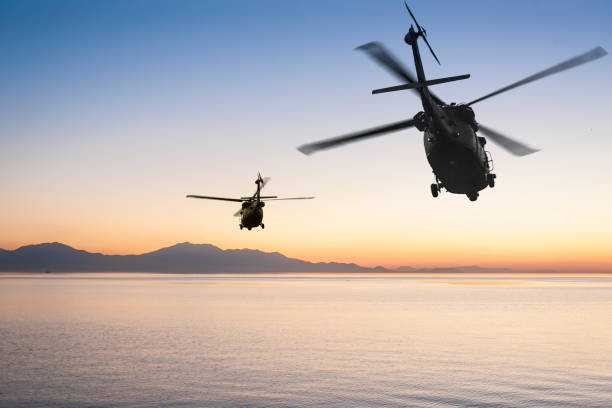 dois helicópteros do exército voando sobre o mar ao pôr do sol - transport helicopter - fotografias e filmes do acervo