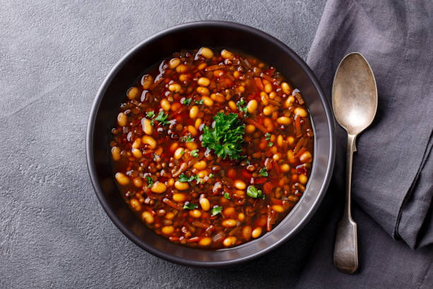 Bean soup in a black bowl. Grey background. Close up. Top view. Bean soup in a black bowl. Grey background. Close up. Top view. red mung bean stock pictures, royalty-free photos & images