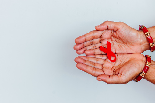 Healthcare and medicine concept - female hands holding red AIDS awareness ribbon