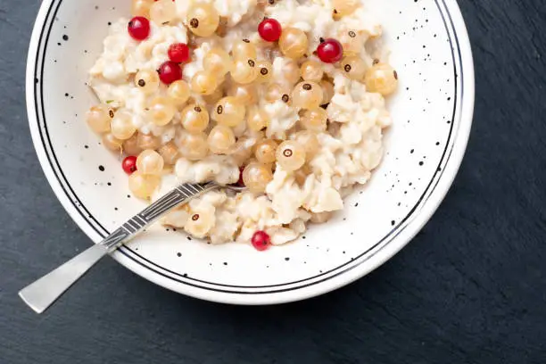 Oatmeal porridge with fresh berries mix on black stone background. Kids menu.