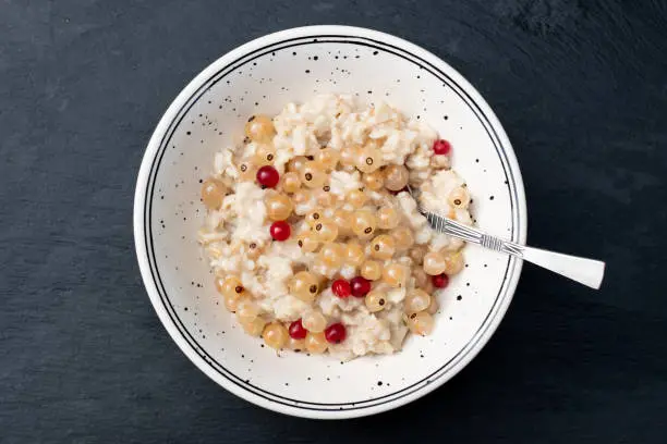 Oatmeal porridge with fresh berries mix on black stone background. Kids menu.