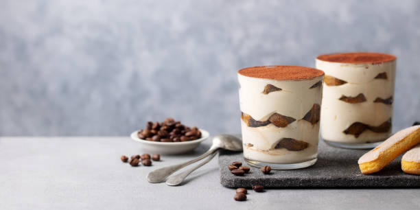 Tiramisu dessert in glass on cutting board. Grey background. Copy space.
