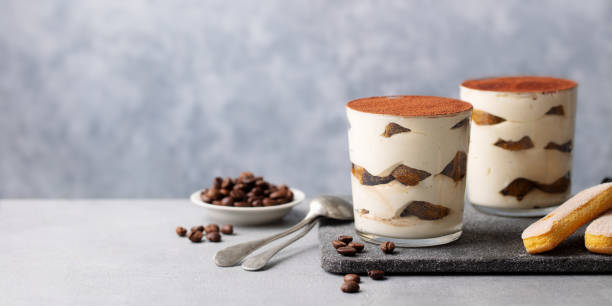 Tiramisu dessert in glass on cutting board. Grey background. Copy space. Tiramisu dessert in glass on cutting board. Grey background. Copy space. tiramisu glass stock pictures, royalty-free photos & images
