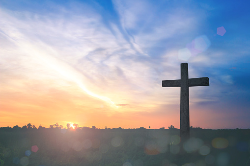 Resurrection of Jesus Christ concept: Silhouette cross on beach autumn sunrise background