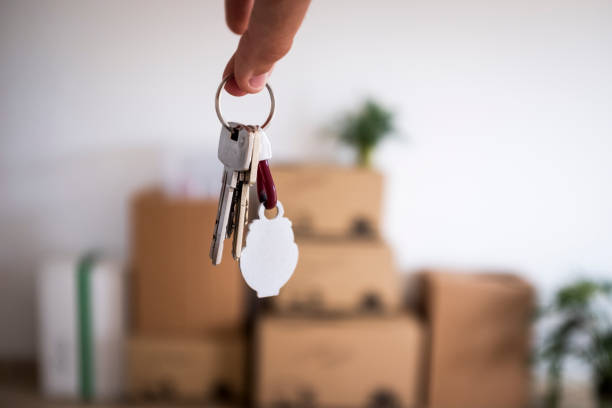 close-up of the keys of the new empty apartment with moving boxes on the floor - key ring fotos imagens e fotografias de stock