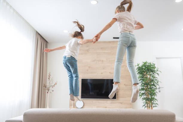 istock Two sisters jumping on couch in living room having fun 1276765191