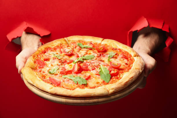 istock Hands hold tasty pizza on red background 1276765972