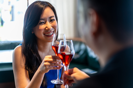 Beautiful young Asian woman having a toast with her partner at a restaurant.