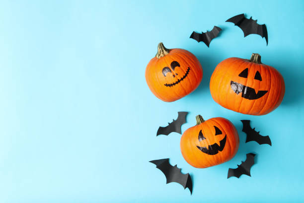 istock Halloween pumpkins and paper bats on blue background 1276766952