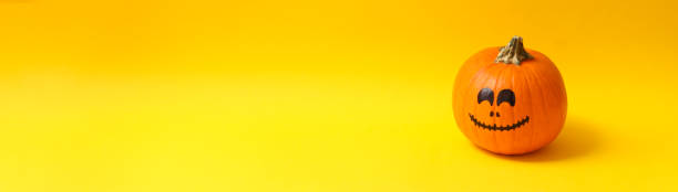 istock Pumpkins with smiling face on yellow background 1276767207