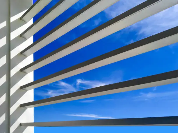 Photo of Sunlight on sunshade battens surface of office building against blue sky background