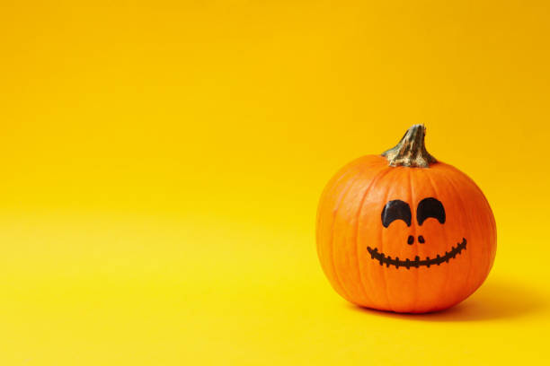 istock Pumpkins with smiling face on yellow background 1276769015