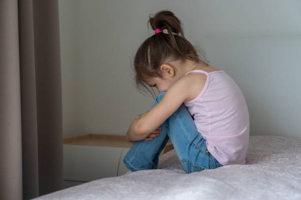 istock A little sad girl sitting on a bed, back view 1276769052