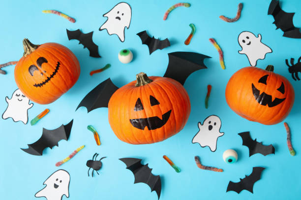 istock Halloween concept with pumpkins, ghosts, candies and bats on blue background 1276769716