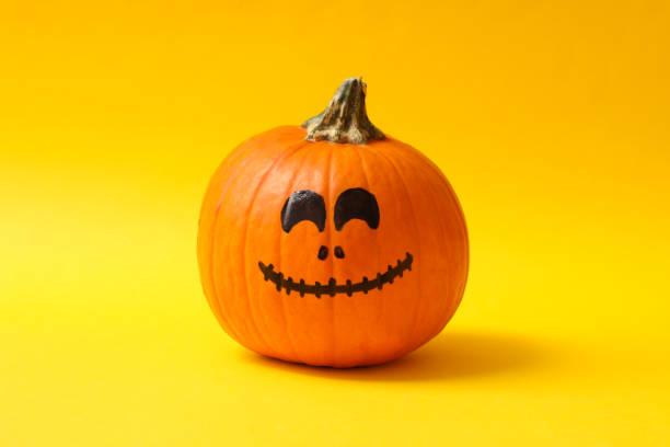 istock Pumpkins with smiling face on yellow background 1276769843