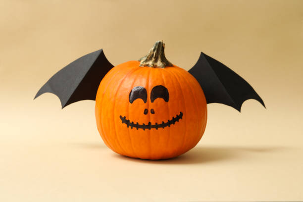 istock Pumpkins with smile and wings on beige background 1276769940