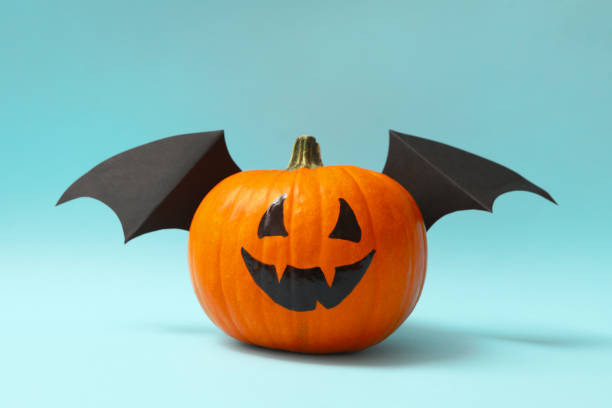 istock Pumpkin with smile and wings on blue background 1276770004