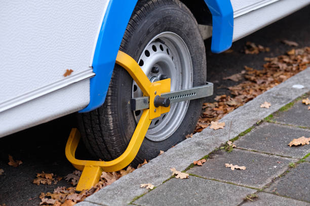 Yellow wheel clamp around the wheel of a caravan Nuremberg, Germany - November 25, 2019: A yellow wheel clamp put aorund the wheel of a caravan to protect the vehicle from being stolen or driven away car boot stock pictures, royalty-free photos & images