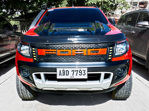 Isolated front view of a new red colored Ford Ranger parked along the road, with dominant grill and big name plate, Philippines, Asia