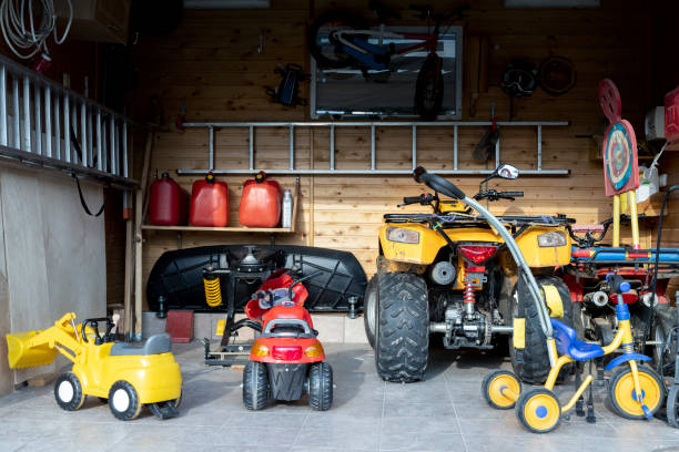 Inside view open door ATV quad bike motorcycle parking messy garage,clutter stuff, children toys and bicylce storage interior at home. House warehouse for tools and equipment . Garage sale facede