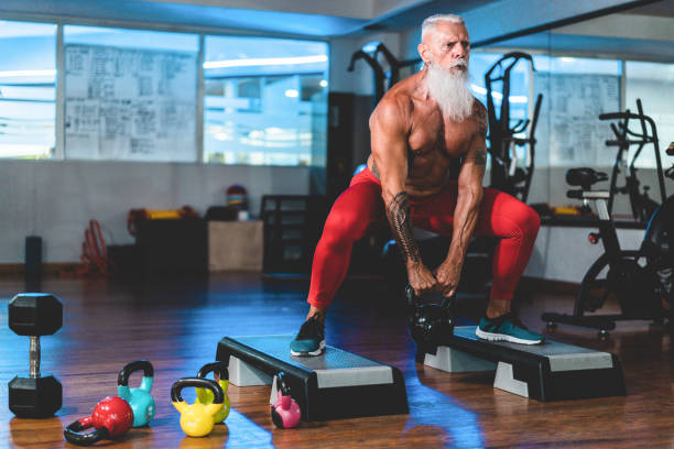 Hipster senior man training inside gym Hipster senior man training inside gym - Mature tattooed person having fun doing workout exercises in sport fitness club - Active elderly lifestyle and fit concept - Focus on face bodyweight training stock pictures, royalty-free photos & images