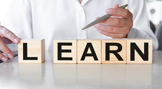 The hand of a businesswoman turns a wooden cube, making up the word LEARN using wooden cubes. Learning, study concept