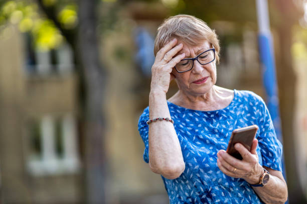 gestresste seniorin mit handy im freien - mobile phone telephone frustration women stock-fotos und bilder