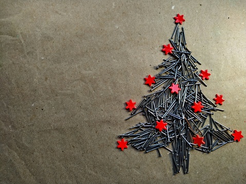 christmas tree folded from construction nails decorated red stars on kraft paper background.