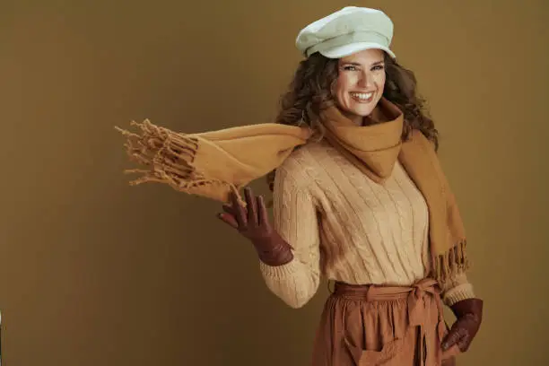 Photo of happy elegant woman in sweater against brown background