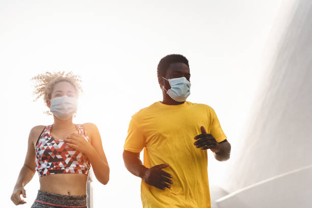istock Young multiracial fit friends running outdoor while wearing face protective masks during coronavirus outbreak - Soft focus on faces 1276780072