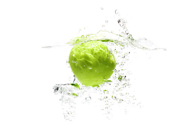 one green apple falling into water on a white background with splashes, drops and bubbles - wet apple imagens e fotografias de stock