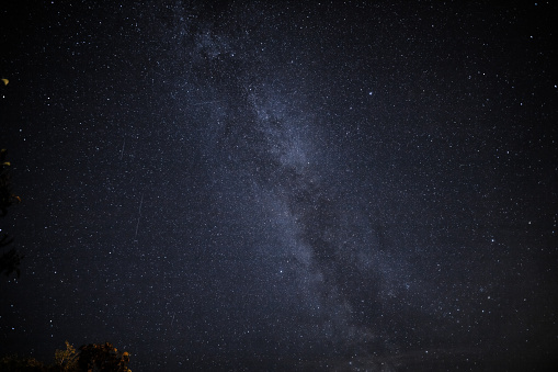 in the night sky you can see the milky way and the traces of satellites