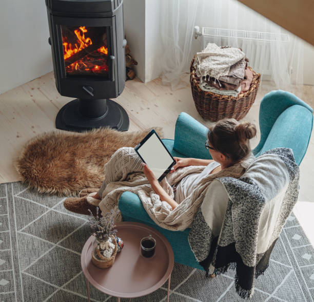 istock woman sitting in cozy armchair, with warm blanket, using tablet 1276789194