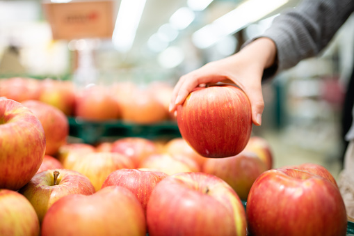 wooden plate with fresh red apples on a light background