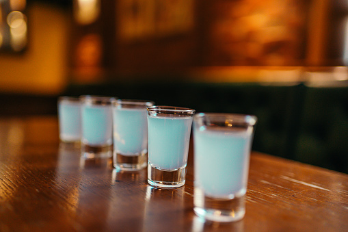 Shots glasses with alcohol served on the bar counter