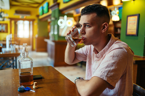 Young man sitting at the bar counter and drinking by himself