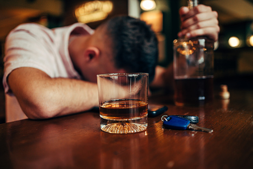 Young caucasian drunk man sleeping on bar counter