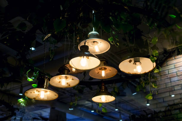 istock retro pendant lanterns with round rusty lights and edison lamp with warm glow hung on ceiling with green leaves eco friendly cafe plants, decorative lighting in interior of night restaurant, nobody. 1276796366