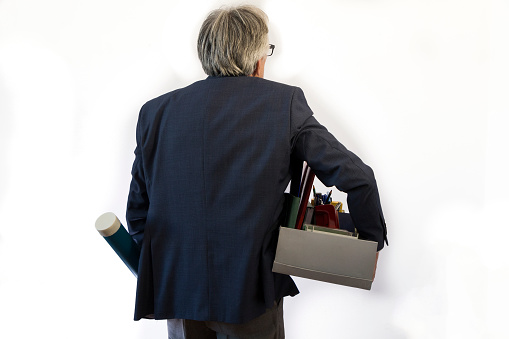 Retired senior businessman leaving the office with his belongings. Isolated on white background.