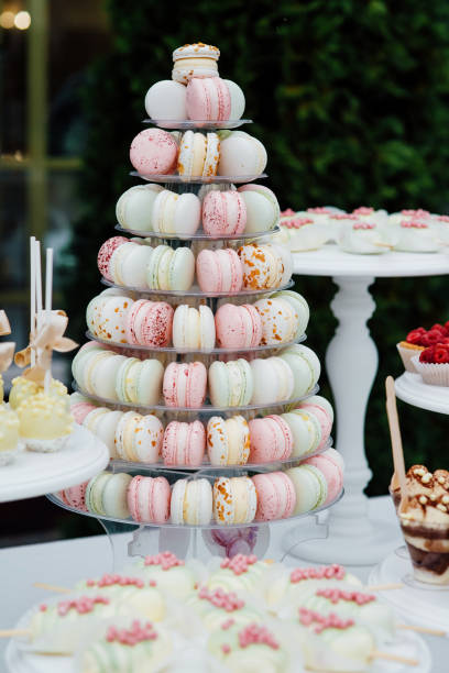 istock Sweet dessert table or candy bar. Wedding party. Natural light. Macaron and meringue pyramid. Cupcakes and marshmallow. 1276802454