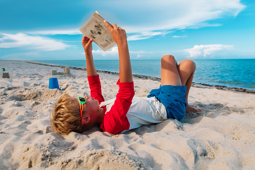 boy reading book at beach vacation, summer reading for kids