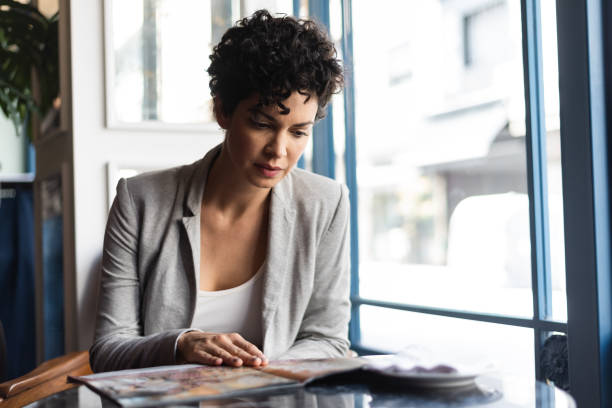 istock Woman looking at menu in restaurant 1276803902